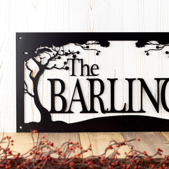 Close up of metal family last name sign with cherry trees, in matte black powder coat. 