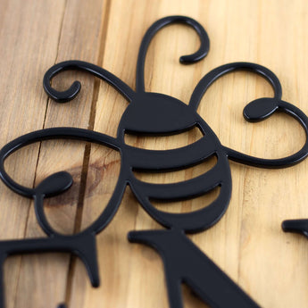 Close up of matte black powder coat on our metal garden name sign with a bumble bee.