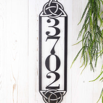 Close up of metal 4 digit vertical house number sign with Celtic knots, in silver vein powder coat.