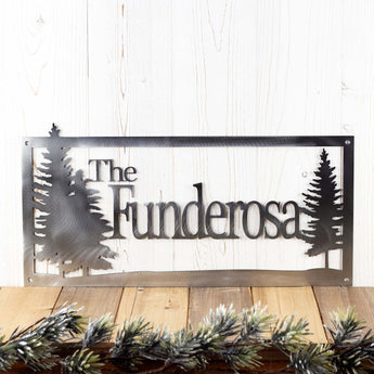 Rectangular personalized family last name metal sign with pine trees, in raw steel. 