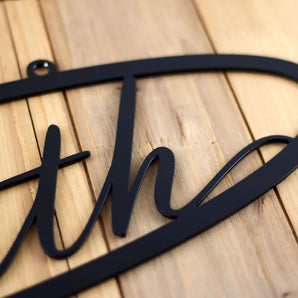 Close up of matte black powder coat on our metal oval family sign with script font.