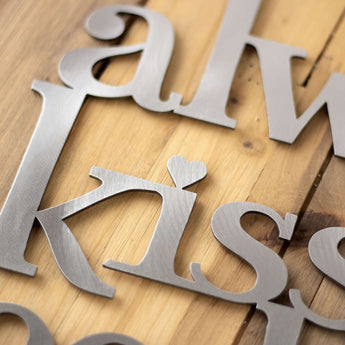 Close up of lettering on our Always Kiss Me Goodnight metal plaque, in raw steel.