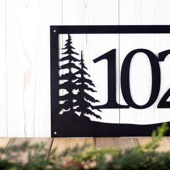 Close up of pine trees on our 3 digit metal house number sign, in matte black powder coat.