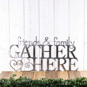Friends & Family Gather Here metal sign with hearts, in raw steel. Placed against a wood wall.