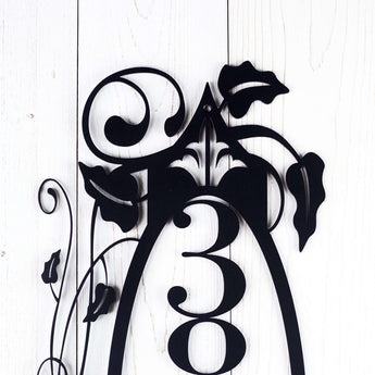 Close up of vines and fleur de lis on our vertical 4 digit metal house number sign, in matte black powder coat. 