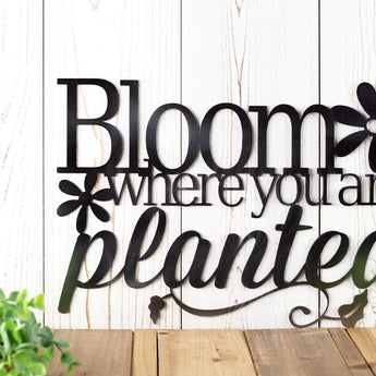 Close up of wording on our Bloom where you are planted metal plaque, in raw steel.