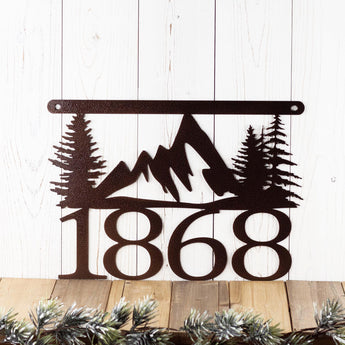 4 digit hanging metal house number plaque with mountains and pine trees, in copper vein powder coat.