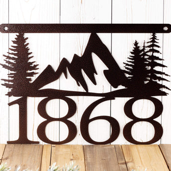 Close up of mountains and pine trees on our hanging metal house number sign, in copper vein powder coat. 