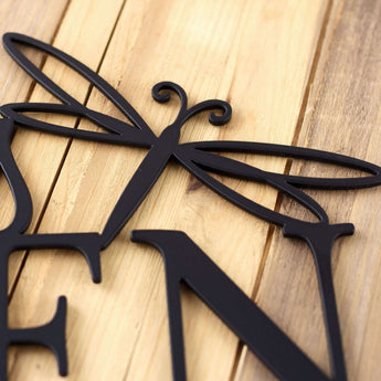 Close up of matte black powder coat on our metal garden name sign with a dragonfly.