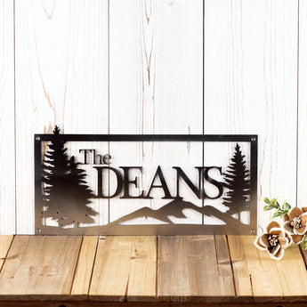 Rectangular personalized metal family name sign, with pine trees and mountain range, in raw steel.