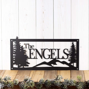 Rectangular personalized metal family name sign, with pine trees and mountain range, in matte black powder coat. 