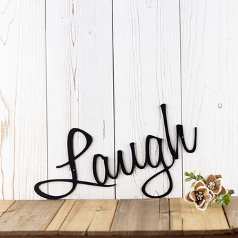 Close up of Laugh script lettering for our Live Laugh Love metal word wall art, in matte black powder coat.
