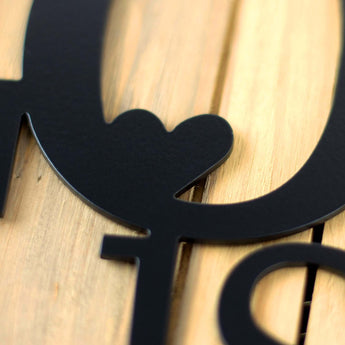 Close up of matte black powder coat on our Love is Rare Treasure It metal wall decor. 