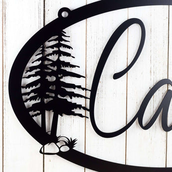 Close up of pine trees on our oval family name sign, in matte black powder coat. 