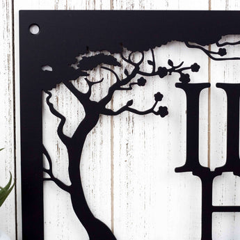 Close up of cherry trees on our custom metal family name sign, in matte black powder coat.