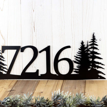 Close up of 4 digit house number sign, in matte black powder coat with pine tree silhouettes.