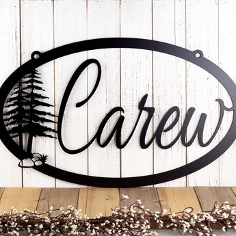 Oval metal family name sign with pine trees, in matte black powder coat. 