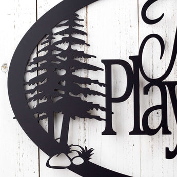 Close up of pine trees on our oval metal family name sign, in matte black powder coat. 