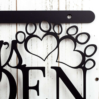 Close up of pet paws on our hanging custom metal name sign, in matte black powder coat.