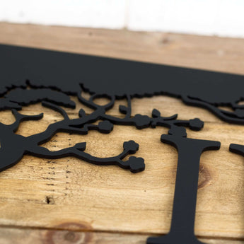 Close up of matte black powder coat on our custom metal sign with cherry trees.