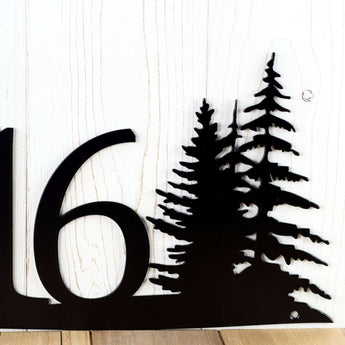 Close up of pine tree silhouettes on our 4 digit metal house number sign, in matte black powder coat.