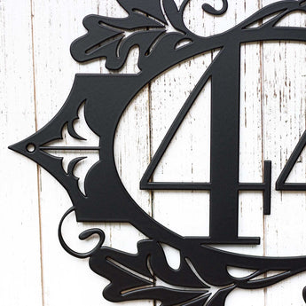 Close up of fleur de lis and fall oak leaves, on our 2 digit metal house number sign, in matte black powder coat.