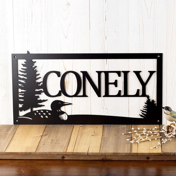 Rectangular metal family last name sign with loon and pine trees, in matte black powder coat.