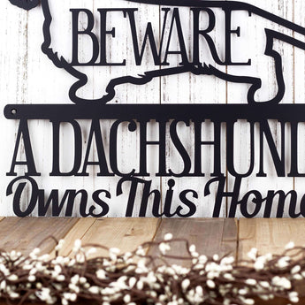 A Dachshund Owns This Home wording on our metal wall art, in matte black powder coat.