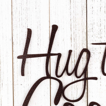 Close up of Hug the Cook! script metal wall art, in copper vein powder coat.