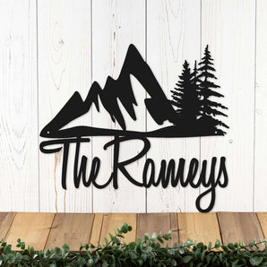 Script personalized family name sign with mountains and pine trees, in matte black powder coat.