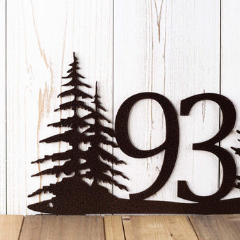 Close up of pine trees on our metal house number sign, in copper vein powder coat.