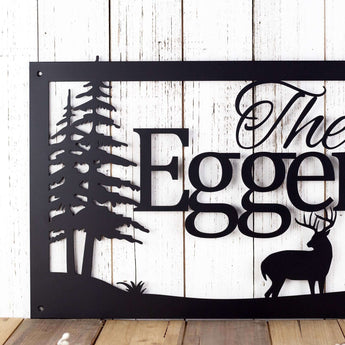 Close up of pine trees on our rectangular family name sign with buck deer, in matte black powder coat.