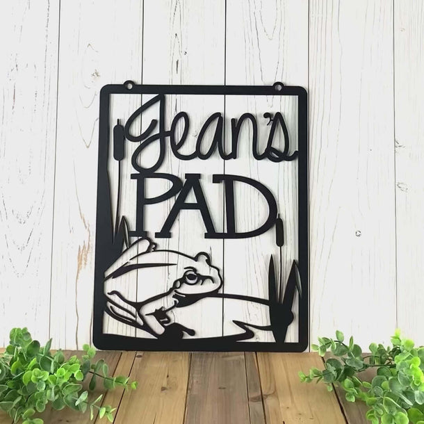 Video of hanging personalized garden name sign with frog and lilypad, in matte black powder coat.
