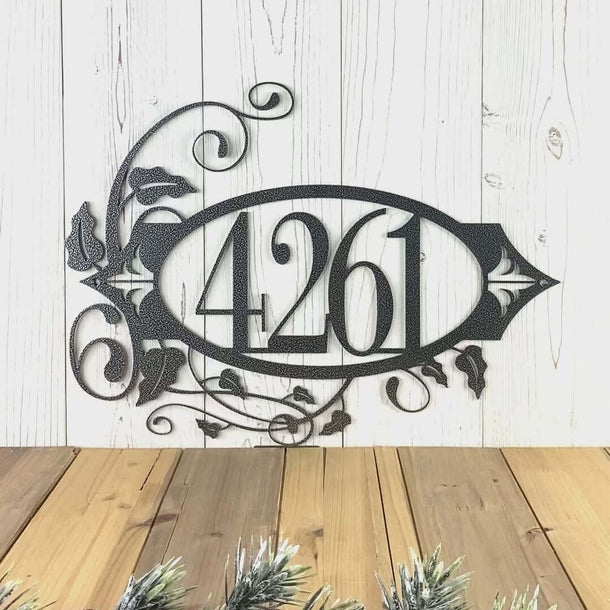 Video of horizontal oval metal house number sign with vines and fleur-de-lis, in silver vein powder coat.