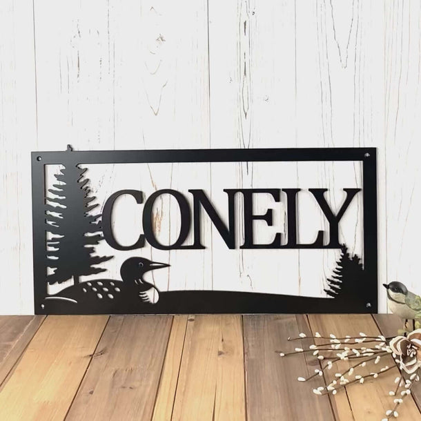 Video of custom metal family name sign with lake loon and pine trees, in matte black powder coat.