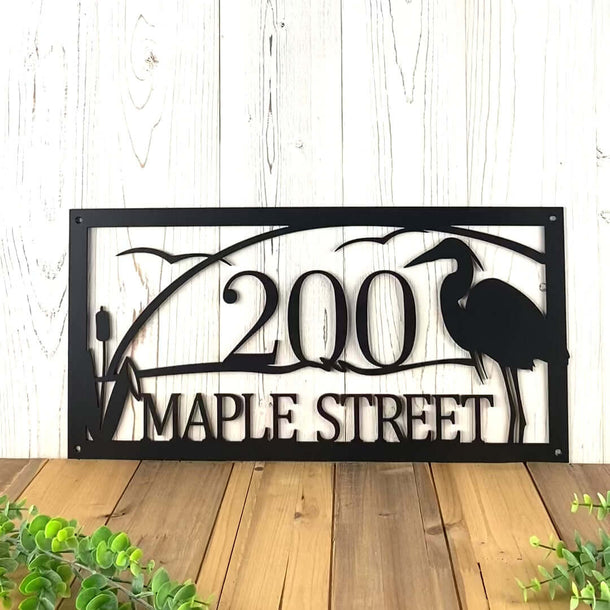 Video of custom family last name metal sign with lake sunset, great blue heron, seagulls and cattails, in matte black powder coat.