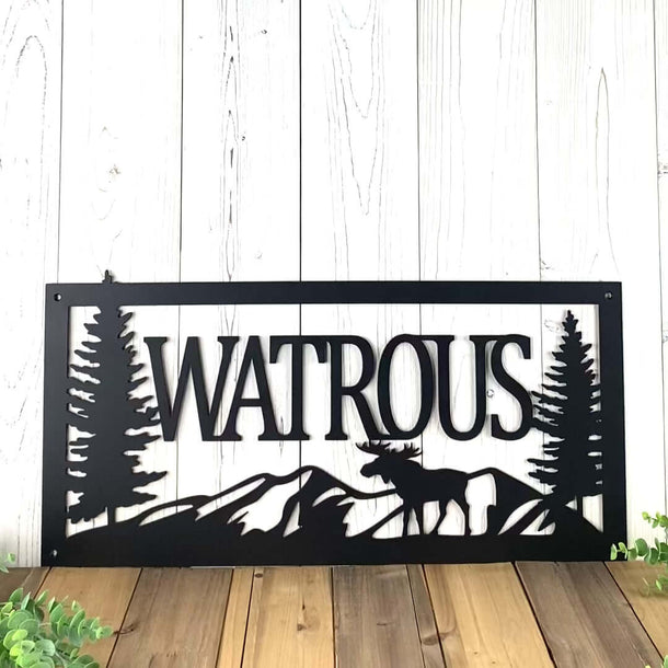 Video of personalized family last name metal sign with moose, mountains, and pine trees, in matte black powder coat.