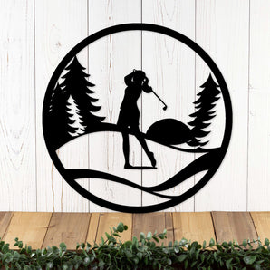 Circular woman golfer metal wall art with pine trees and sunset, in matte black powder coat.